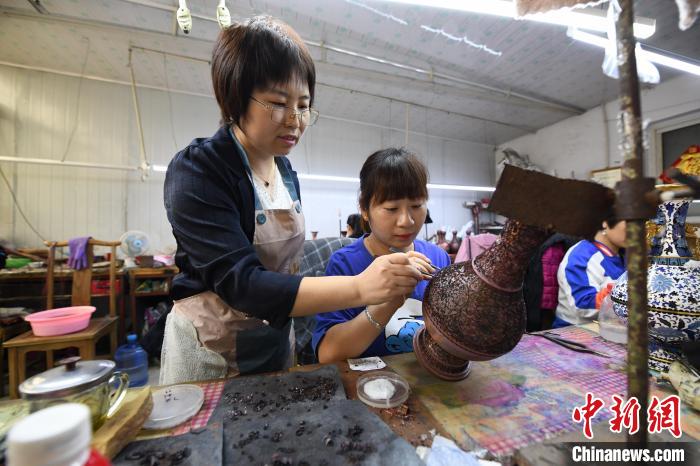 图为河北省巧手脱贫示范基地总工艺师王静正在指导女工为景泰蓝工艺品“掐丝”。